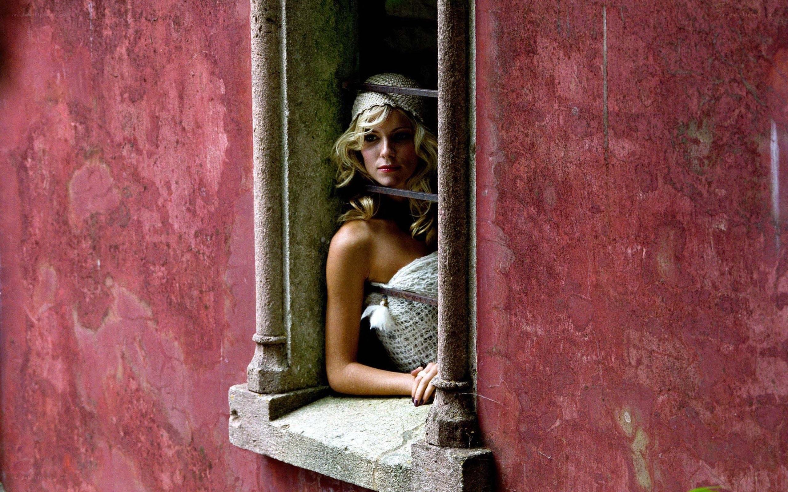 woman in window with red wall