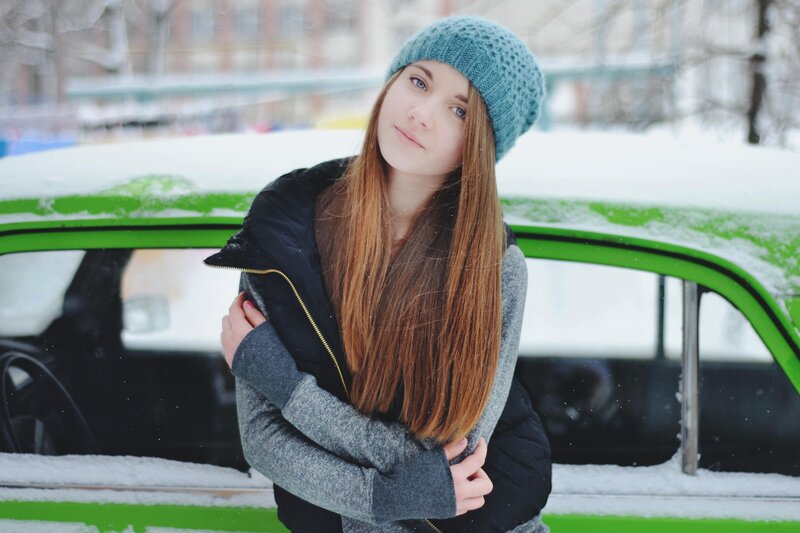 Woman in winter by a green car