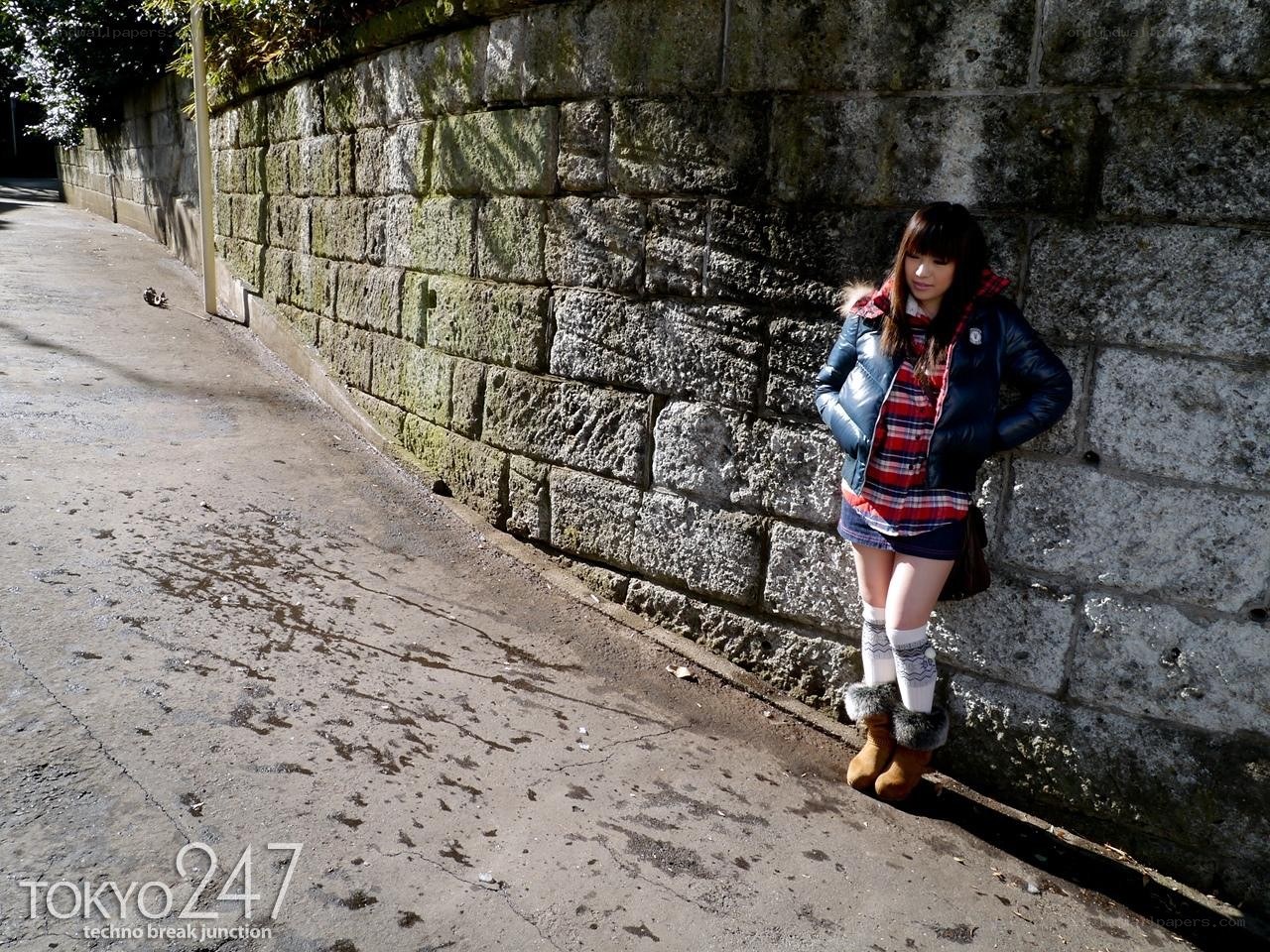 woman in winter clothes by wall