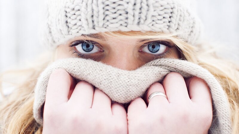 woman in winter hat covering face