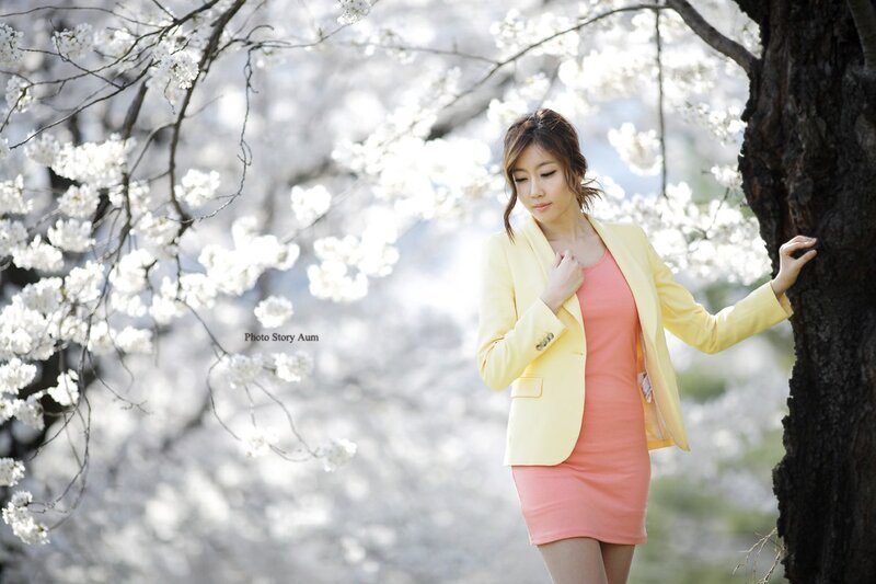 Woman in yellow blazer under cherry blossoms