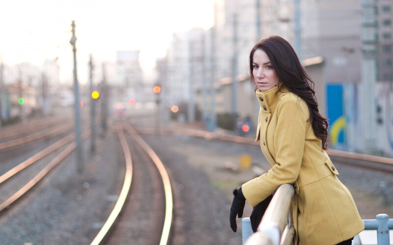 Woman in yellow coat by train tracks