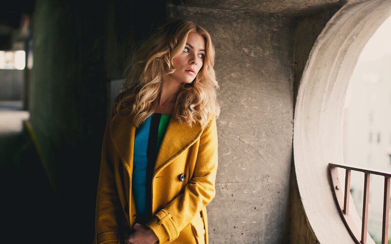 woman in yellow coat by window