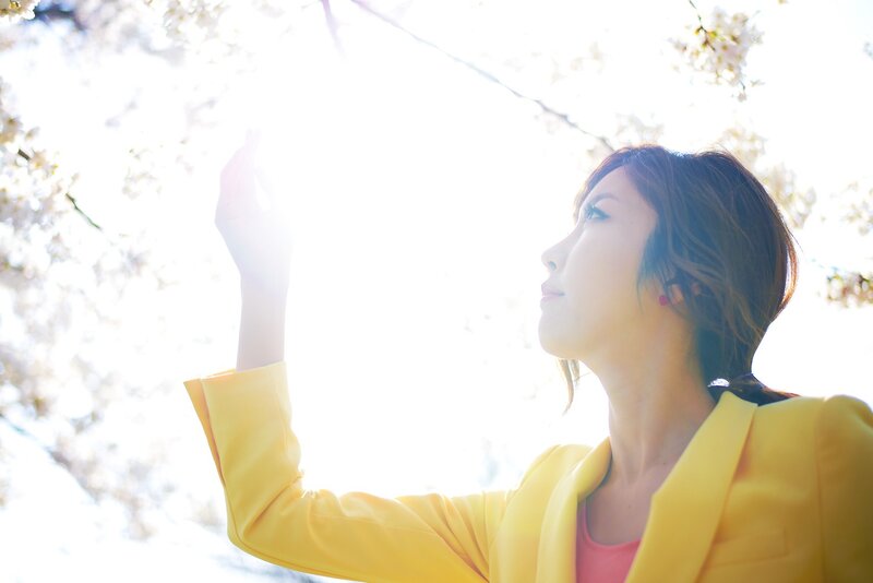 woman in yellow coat under blossoms