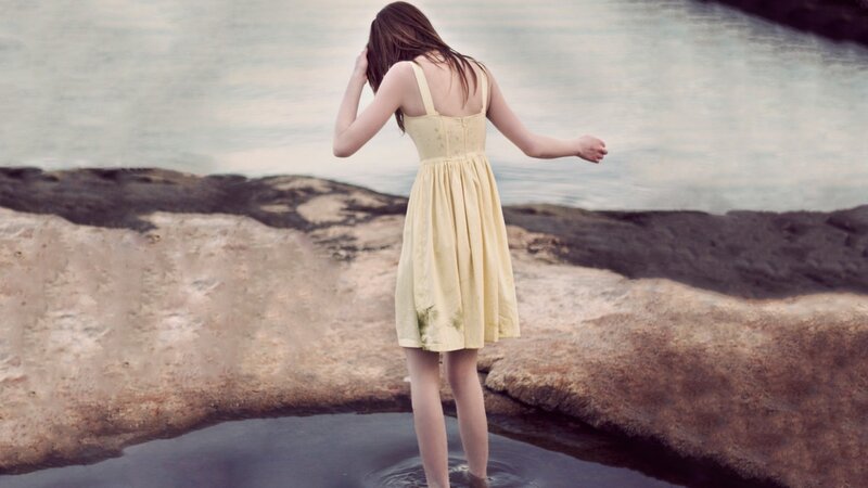 woman in yellow dress at water's edge