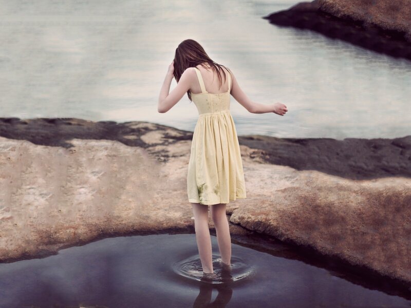 woman in yellow dress at water's edge