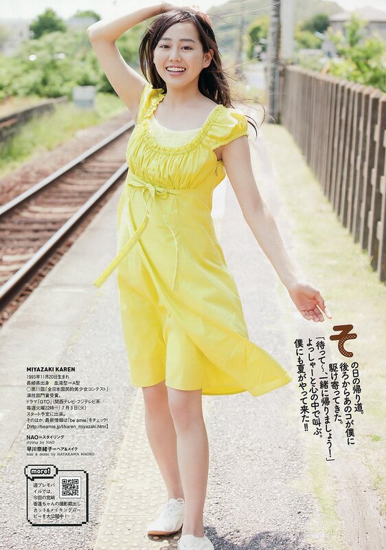 Woman in yellow dress by train tracks