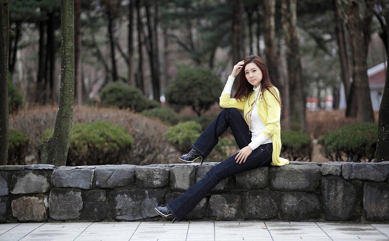 Woman in yellow jacket sitting on wall