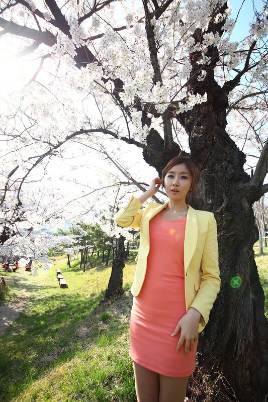 Woman in yellow jacket under cherry blossoms