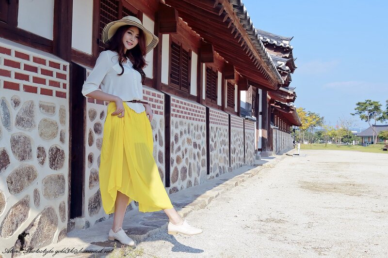 Woman in yellow skirt at traditional building