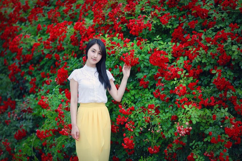 woman in yellow skirt by red roses