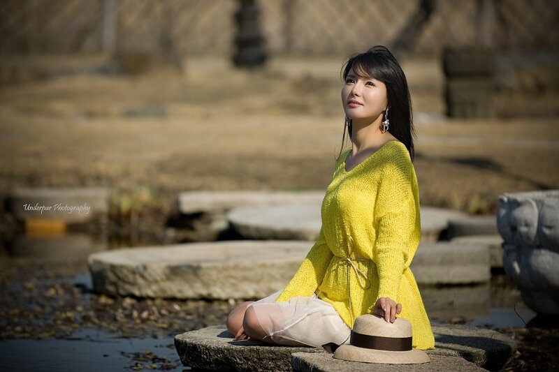 Woman in yellow sweater by pond