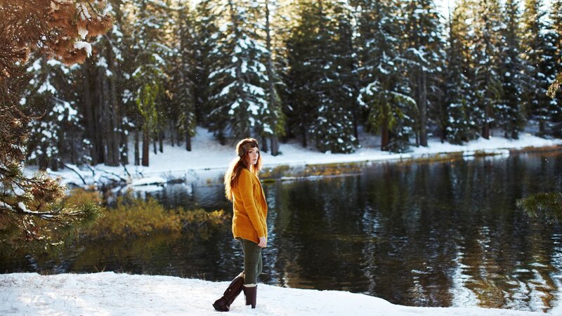 Woman in yellow sweater by snowy lake