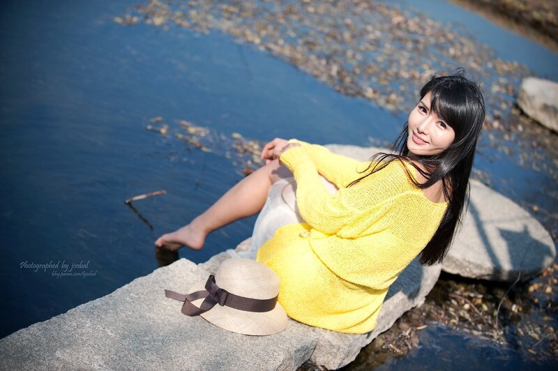 Woman in yellow sweater by water