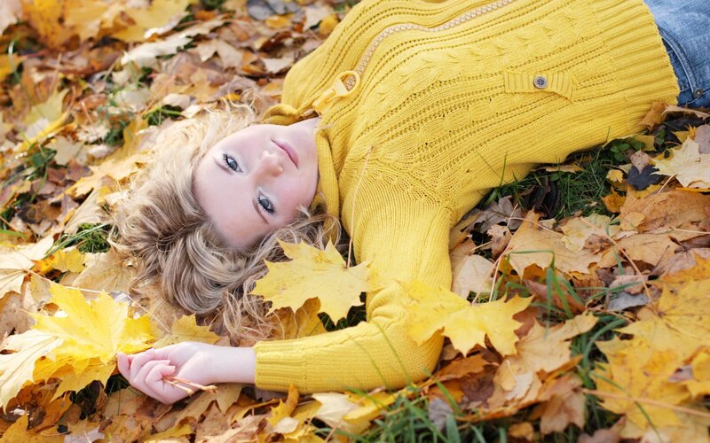woman in yellow sweater on autumn leaves