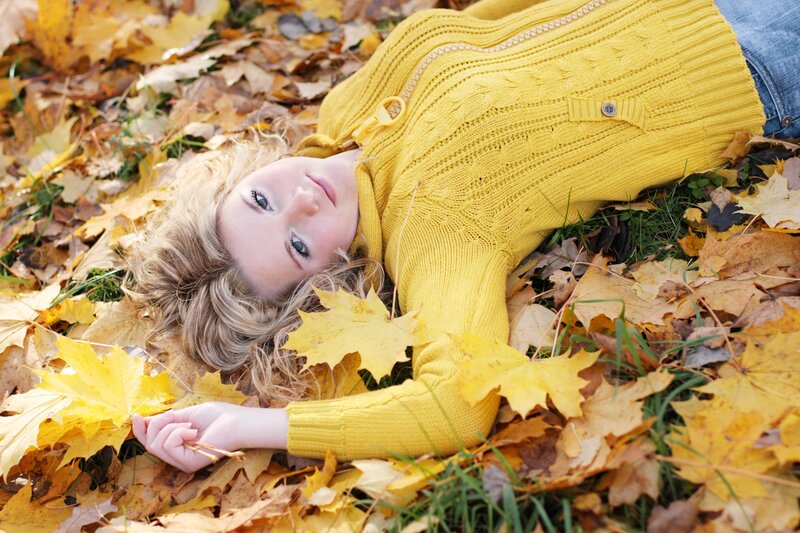 Woman in yellow sweater on autumn leaves