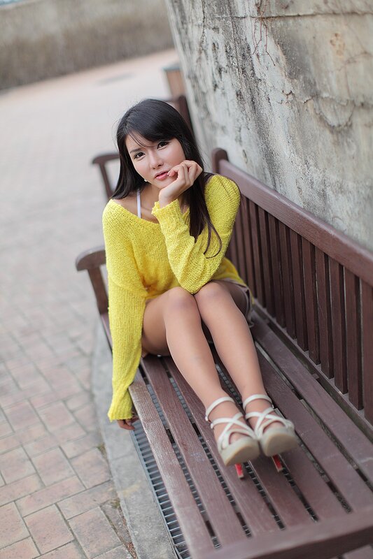 Woman in yellow sweater on bench