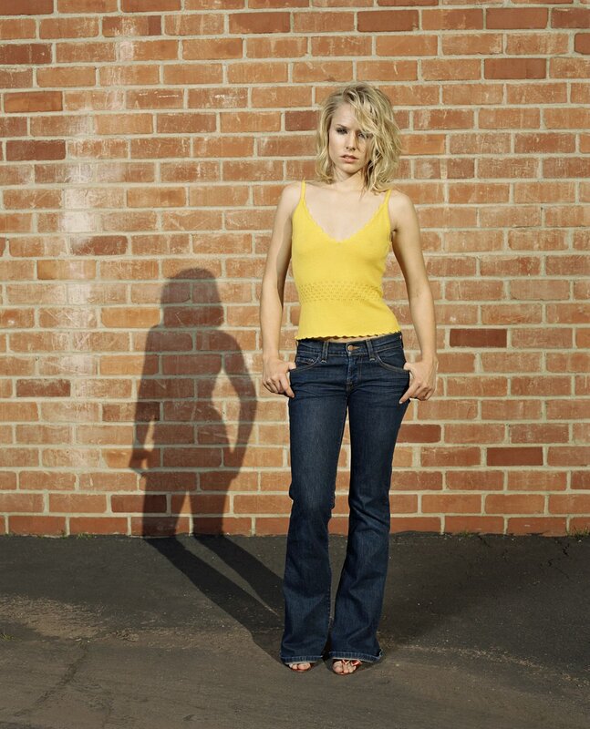 Woman in yellow top against brick wall