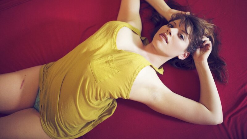 woman in yellow top lying on bed