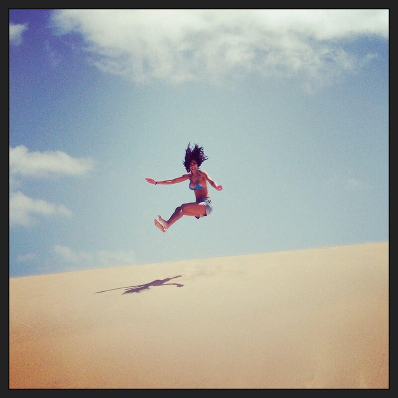 woman jumping on a sand dune