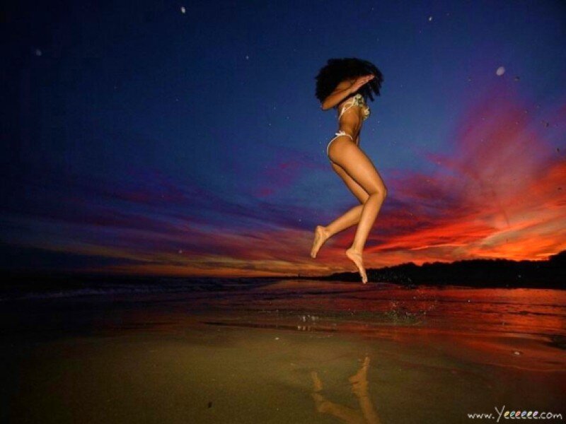 Woman jumping on beach at sunset