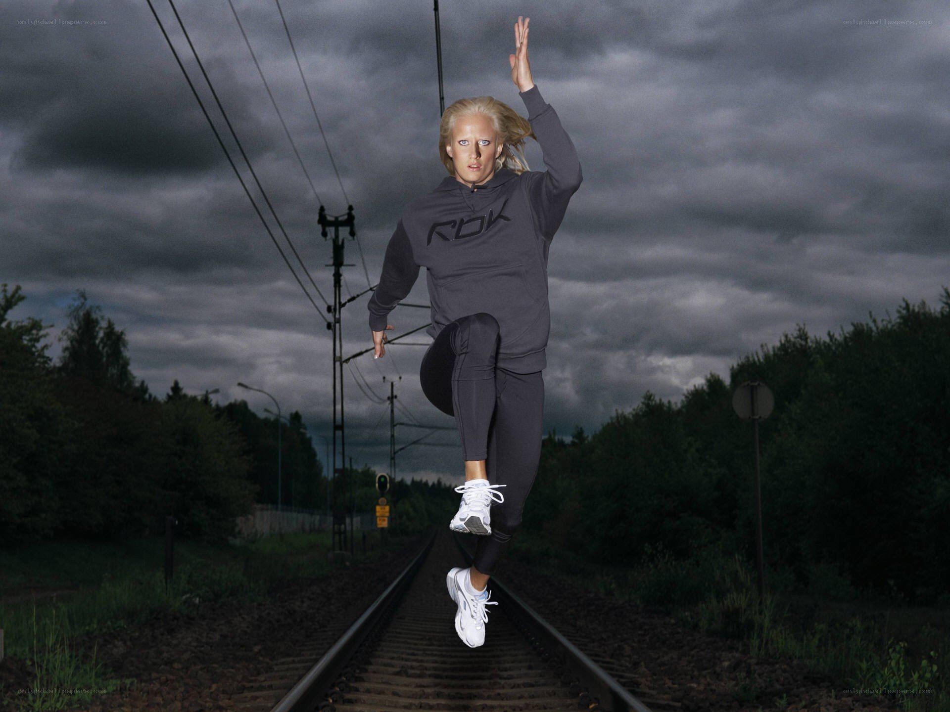 Woman jumping on train tracks