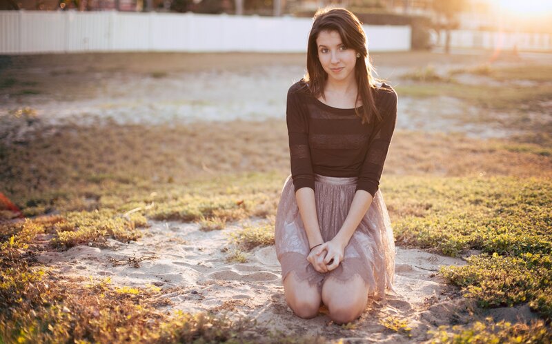 woman kneeling on sand at sunset