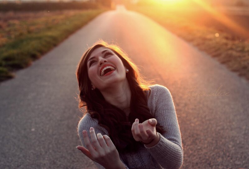 woman laughing on a road at sunset