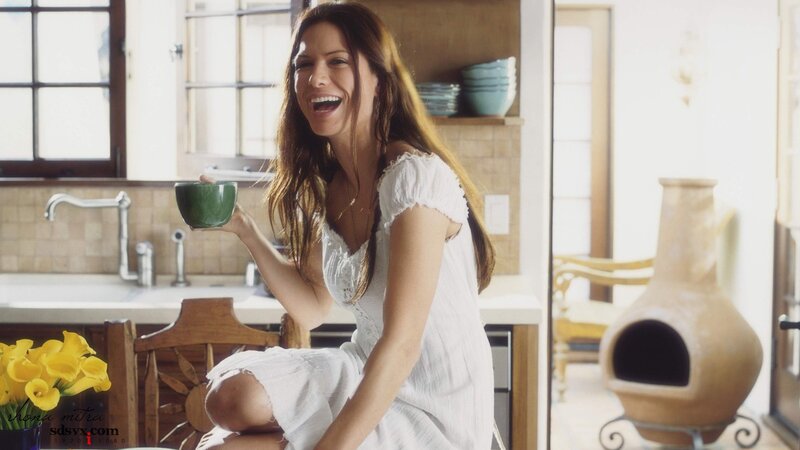 woman laughing with cup in kitchen