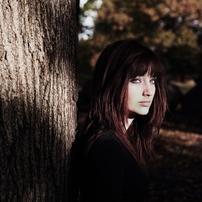 woman leaning against a tree