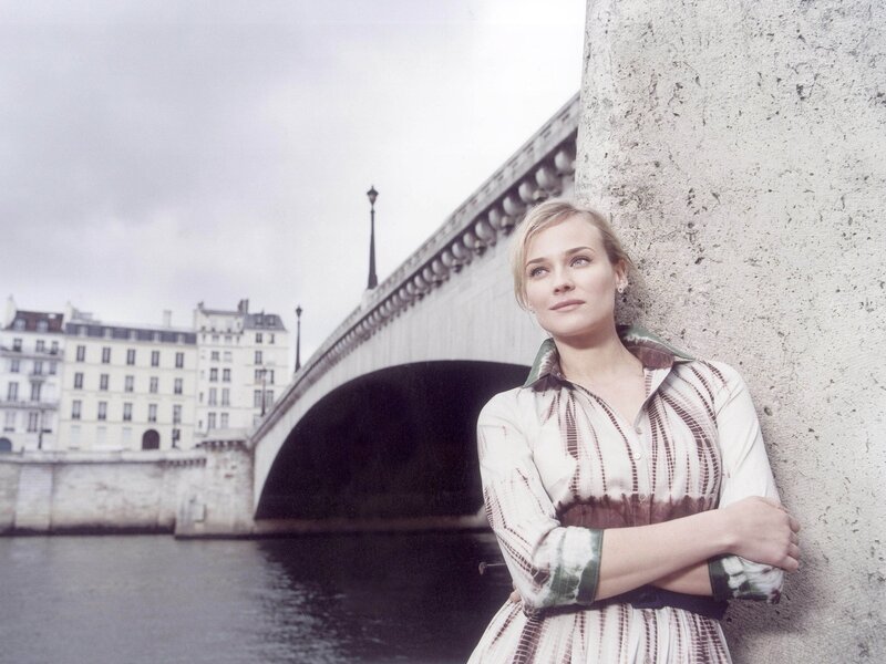 woman leaning against a wall by a bridge