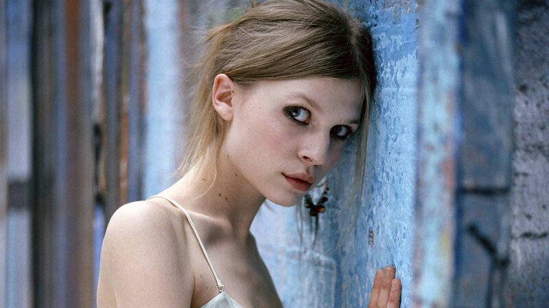 woman leaning against blue wall