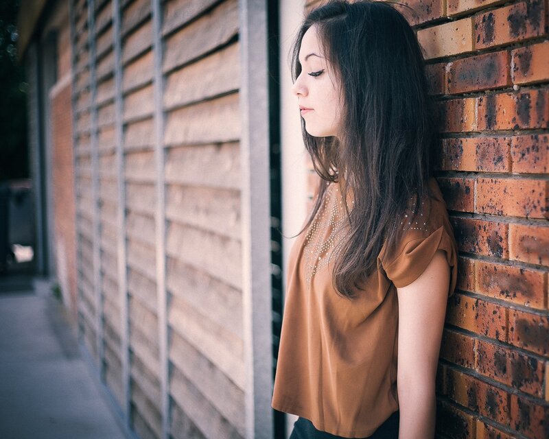 woman leaning against brick wall