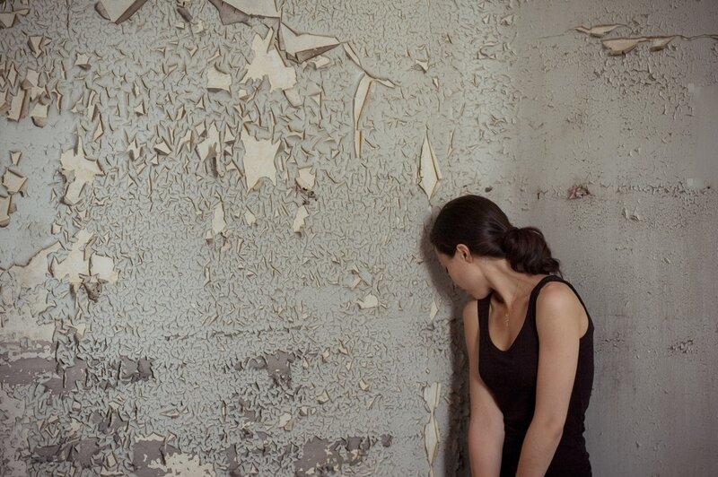 woman leaning against peeling wall