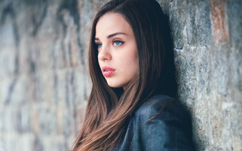 woman leaning against stone wall