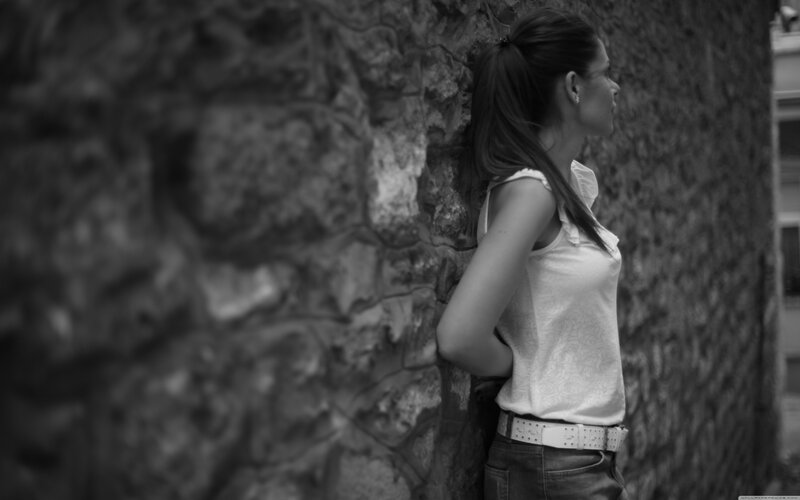 woman leaning against stone wall
