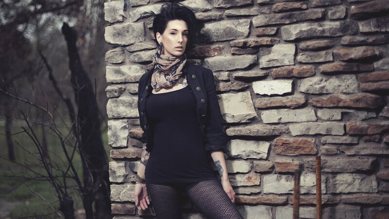 woman leaning against stone wall