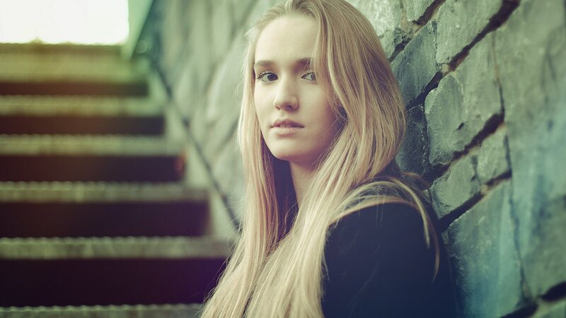 woman leaning against stone wall