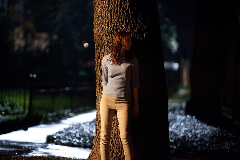 woman leaning against tree at night