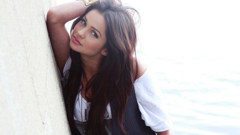 woman leaning against wall by water