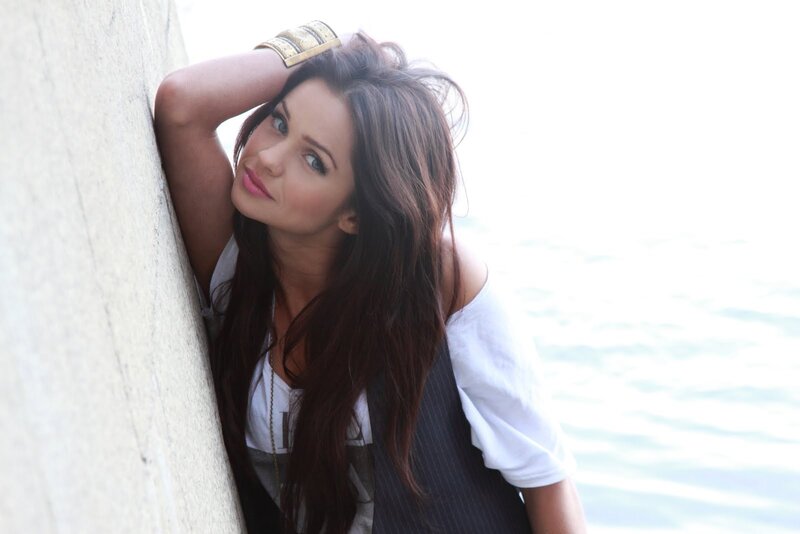 woman leaning against wall by water