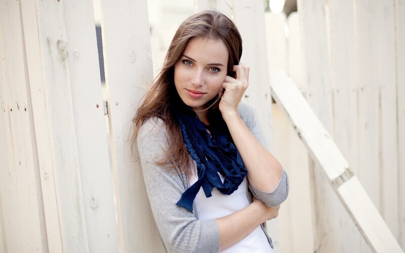woman leaning against white fence