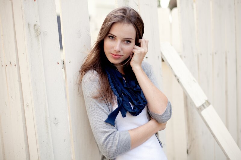 woman leaning against white fence