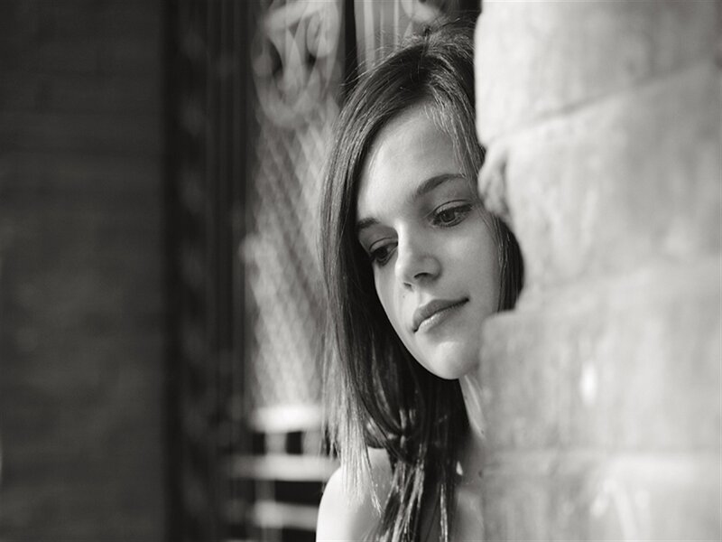 Woman Leaning on Brick Wall — Black, Contemplative