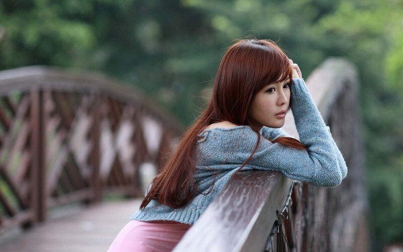 woman leaning on bridge railing