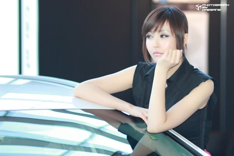 woman leaning on car at show