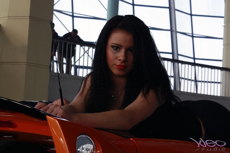 Woman Leaning on Orange Car — Dramatic, Photograph, Building Interior