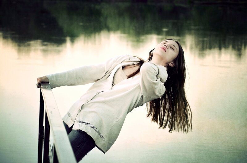 woman leaning on railing by water