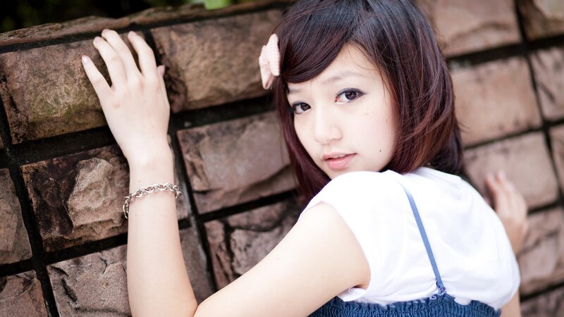 woman leaning on stone wall