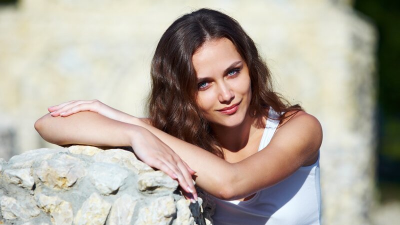woman leaning on stone wall